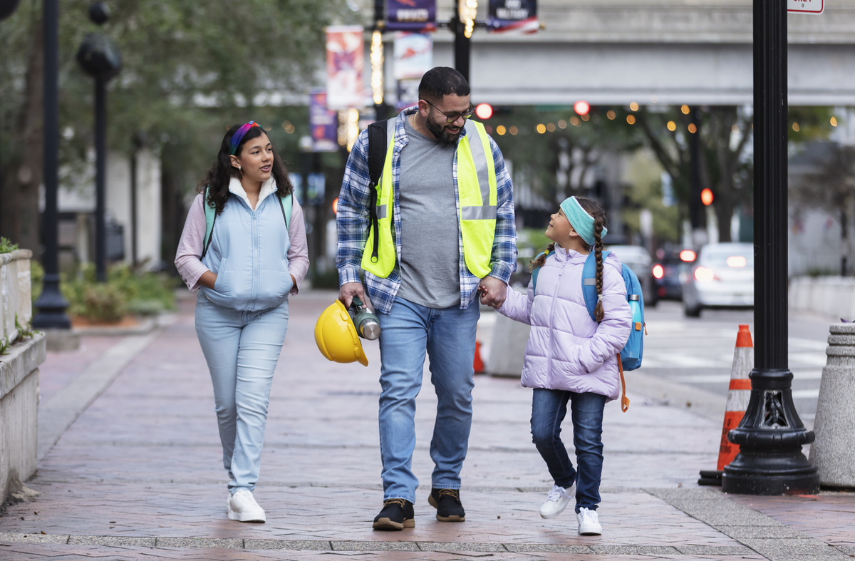 Hispanic father taking daughters to school in city Hispanic father taking daughters to school in city