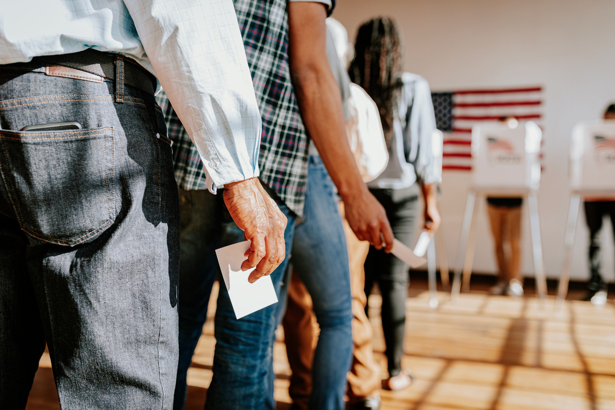 Diverse people in line voting in election, holding ballots Diverse people in line voting in election, holding ballots